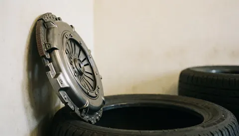 Metal clutch plate leaning against tires in an auto repair garage with a blurred background