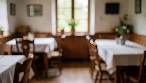 Interior of a rural restaurant with white tablecloths, wooden chairs, and natural light from the window, suitable for text background.