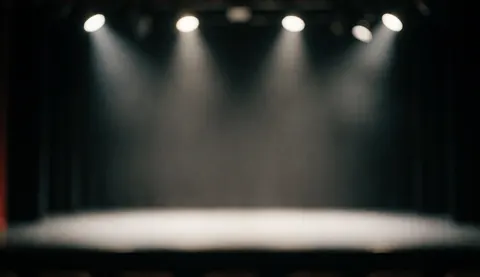 Empty dance stage floor illuminated by dramatic stage lights against a dark background, creating a professional atmosphere suitable for text overlays.