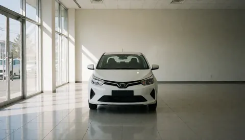 White vehicle displayed in a car dealership showroom featuring reflective flooring, neutral walls, and natural light from glass windows.