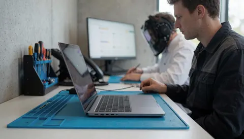 Laptop placed on an anti-static mat ready for computer repair service in a workspace with concrete walls.