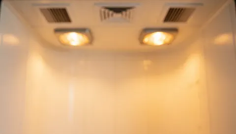 Blurred interior of a curing booth with infrared lights and curved white walls, ideal for automotive paint text backgrounds.