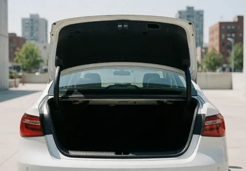 White sedan parked on urban pavement with open trunk during daylight, suitable for ride-hailing and transport services.