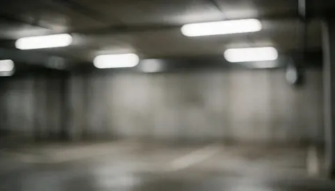Blurred underground garage background featuring concrete walls and fluorescent lights, suitable for tow truck service advertisements