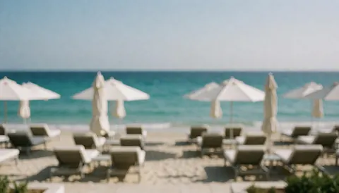 Beach background with chairs and umbrellas, ideal for text, featuring turquoise water and light sand.
