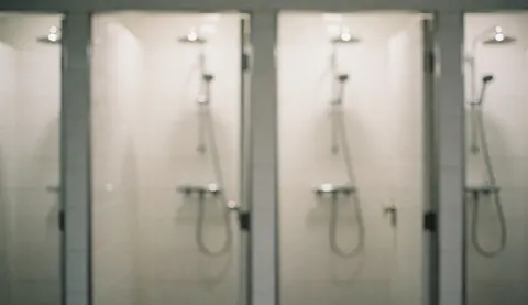 Shower heads with metal faucets in a bathroom with white tiled walls, suitable for commercial text backgrounds