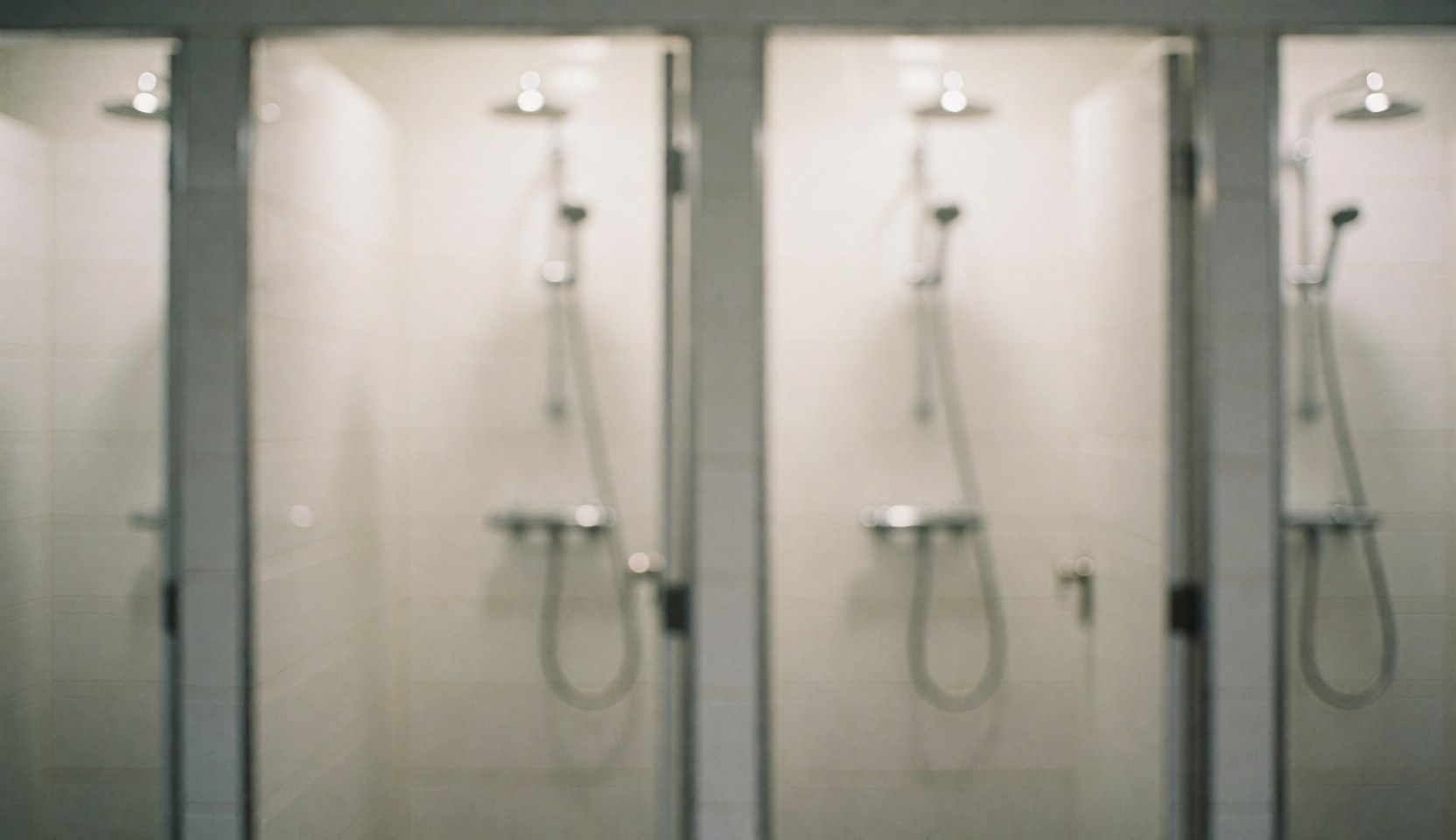 Shower heads with metal faucets in a bathroom with white tiled walls, suitable for commercial text backgrounds
