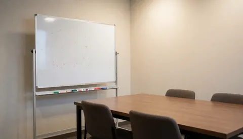 Professional meeting room featuring a whiteboard, wooden table, and chairs, suitable for volleyball coaches.
