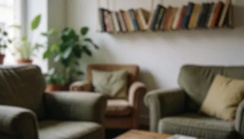 Cozy living room background featuring upholstered armchairs, a floating bookshelf, and green plants, ideal for bed and breakfast hospitality text overlays.