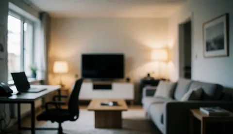 Modern living room featuring a gray sofa, television, and wooden tables illuminated by warm light, suitable for business text backgrounds.