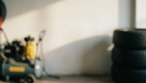 Background of a tire shop featuring stacked tires and compressed air equipment with light walls and natural lighting suitable for text overlay
