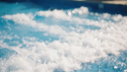 Blurred waves in a water park pool with bright sunlight, ideal for commercial text backgrounds
