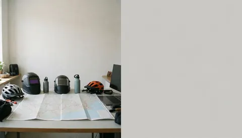 Desk with trail map, bicycle helmets, water bottles, and laptop for planning mountain bike routes
