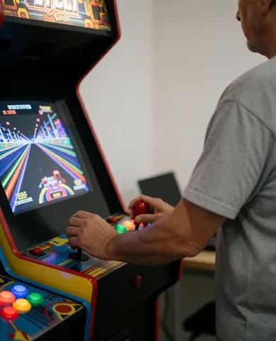 Close-up of an adult playing a racing arcade game with colorful buttons and a bright screen