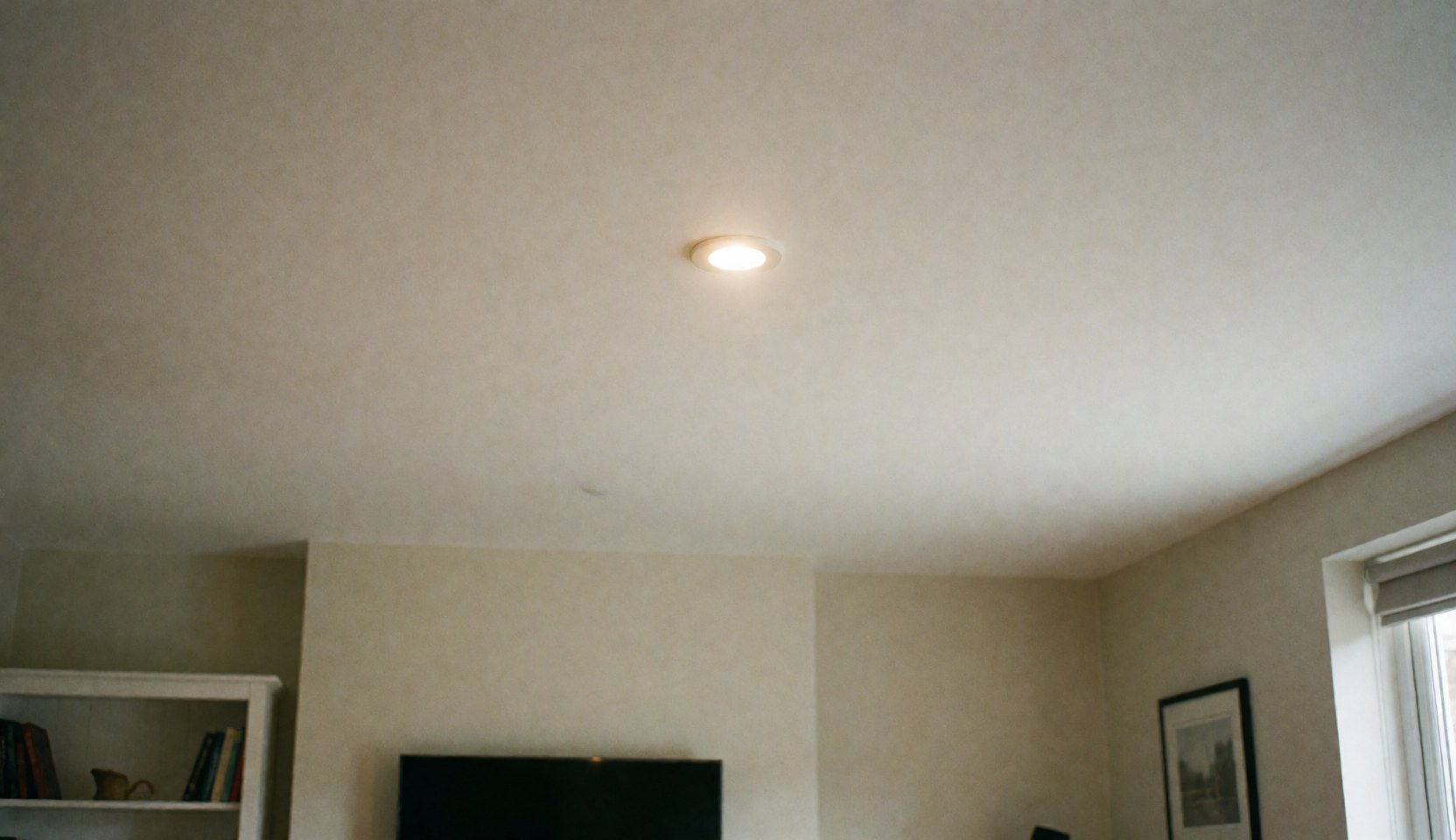 Recessed LED ceiling light in a living room with clean smooth walls, providing a professional background for residential electrical service text.