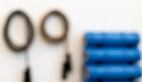 Out of focus boxing gym background featuring ropes and blue rollers against a white wall, suitable for text overlay