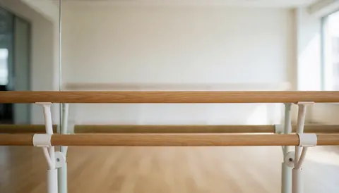Wooden ballet barre in a dance studio with mirrors and light floor, professional background for text.