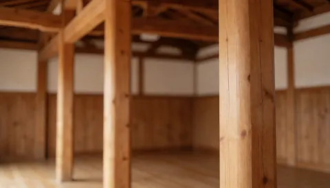 Close-up view of wooden beams in an empty dojo with wooden walls and floor, suitable as a text background for martial arts school websites.