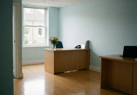 Clean and welcoming clinic reception area featuring a wooden table, fresh flowers, and blue walls with natural light.