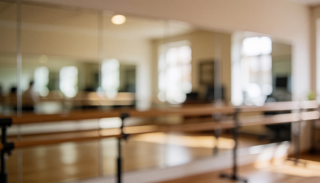 Soft focus background of a dance studio featuring wooden barres, mirrors, beige walls, and warm lighting, ideal for text overlay.