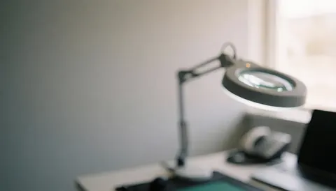 Magnifying glass resting on an anti-static mat on a repair table with soft lighting and a professional gray background for computer repair services.