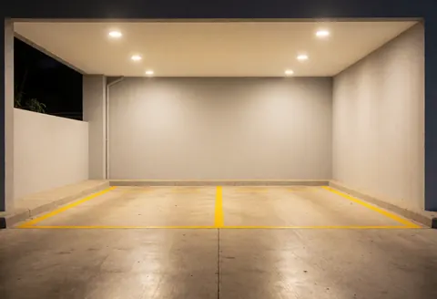 Empty taxi parking area featuring yellow painted lines, light walls, and polished pavement ready for night service.