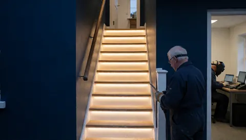 Modern staircase with integrated blue LED lighting and blue walls during professional installation work