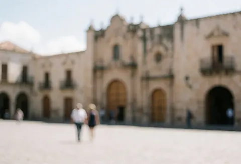 A colonial plaza featuring historic buildings and architecture, with people walking around, suitable for urban tour text backgrounds.
