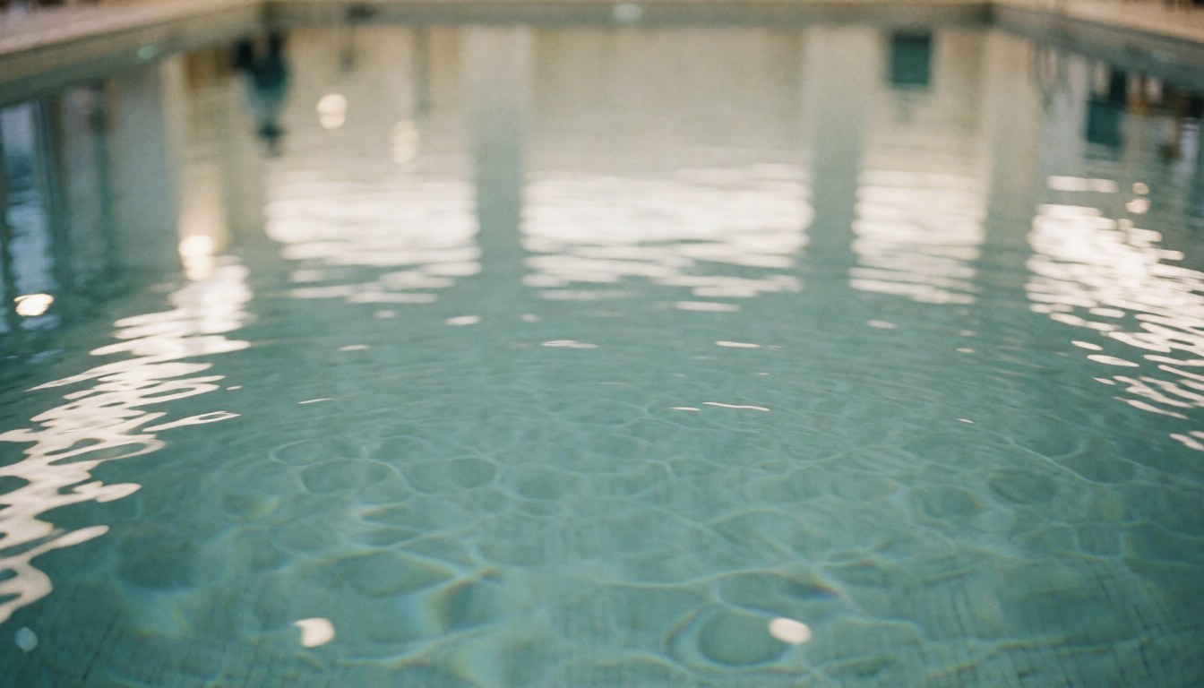 Clear serene indoor swimming pool water with soft light reflections, suitable as a background for swimming training content.