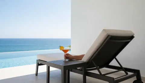 A pool chair with a cocktail overlooking the ocean, ideal for a resort website hero image