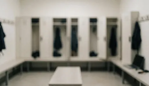 Empty martial arts locker room featuring white lockers, benches, and soft diffused lighting, providing a clean background for text overlays.