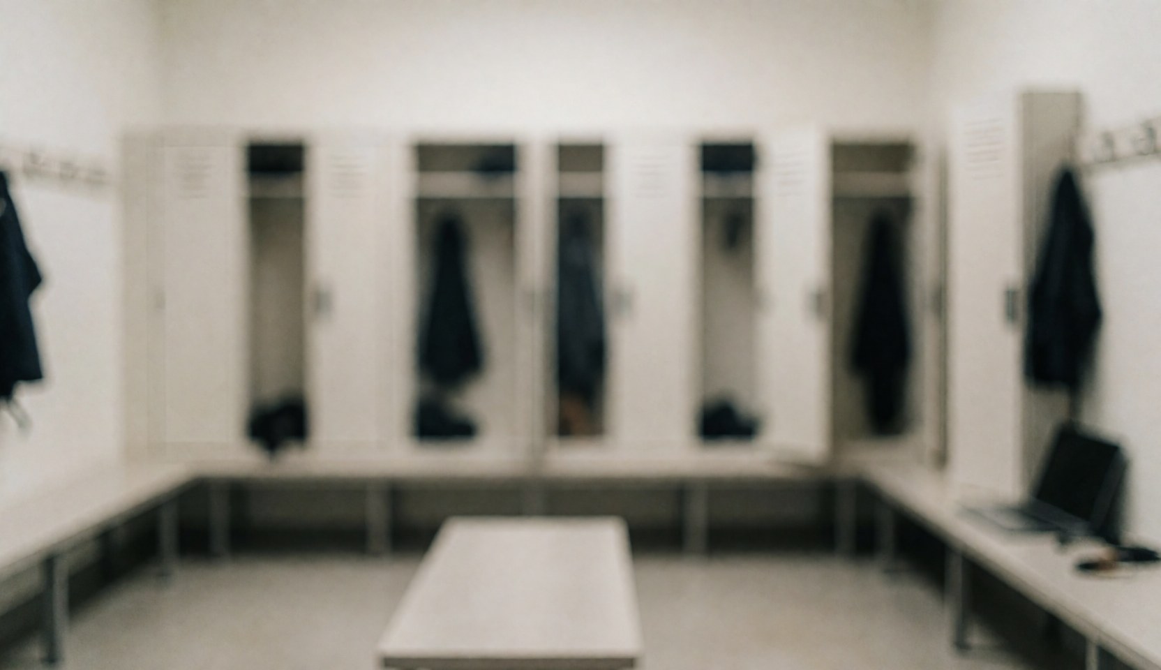 Empty martial arts locker room featuring white lockers, benches, and soft diffused lighting, providing a clean background for text overlays.