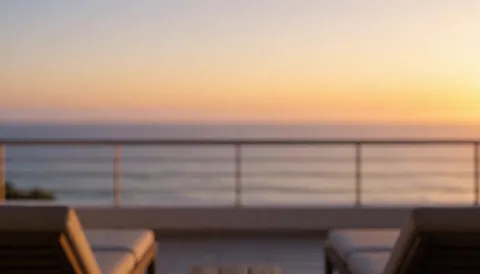 Terrace with beach chairs overlooking the ocean at sunset, featuring golden light and an orange and purple gradient background ideal for text overlay