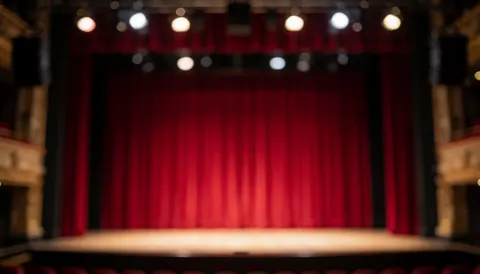 Empty stage with red curtains and soft bokeh lighting, ideal background for promotional text and event announcements