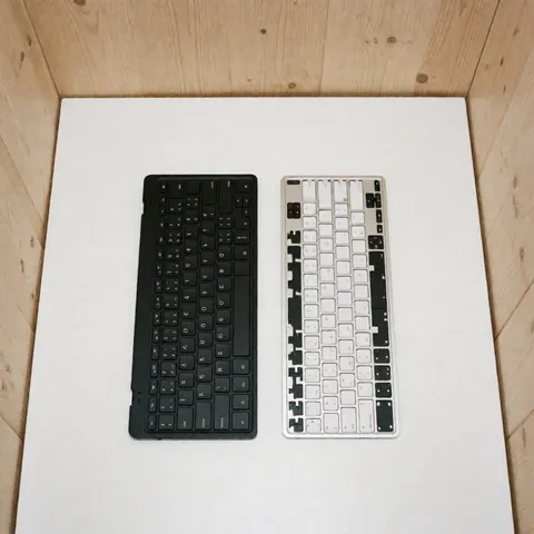 A full black keyboard and a white keyboard without keys on a white surface for computer repair