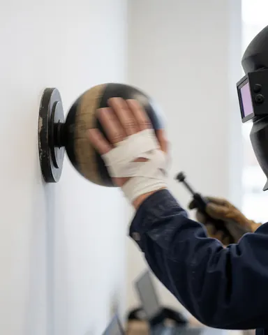 Close-up of a hand wrapped in bandage striking a speed ball against a white wall, showing boxing training equipment.