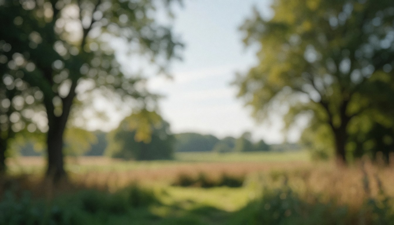 Softly blurred countryside scene featuring trees and open fields, creating a serene natural background suitable for text overlays.