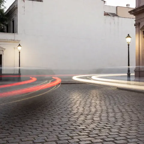 Long exposure light trails from cars and streetlamps on a historic cobblestone plaza at night