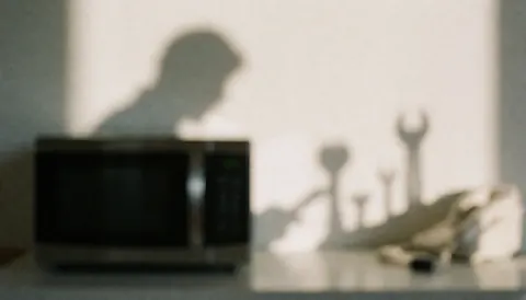 Shadows of tools cast on a microwave surface, creating a professional background ideal for microwave repair service advertisements.