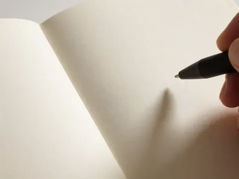 A black pen resting on textured paper, highlighting surface details and warm lighting for product photography.