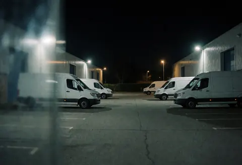 Cargo trucks parked in an industrial park at night with warm lighting highlighting the logistics and freight transport environment