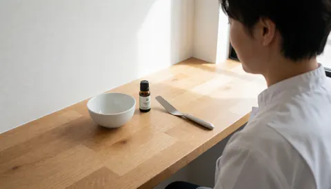 Close-up of hands organizing skincare tools and products on a clean wooden surface with natural lighting