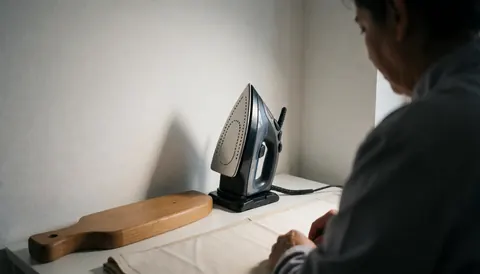 A steam iron resting on its base next to a wooden board at a professional pressing station.