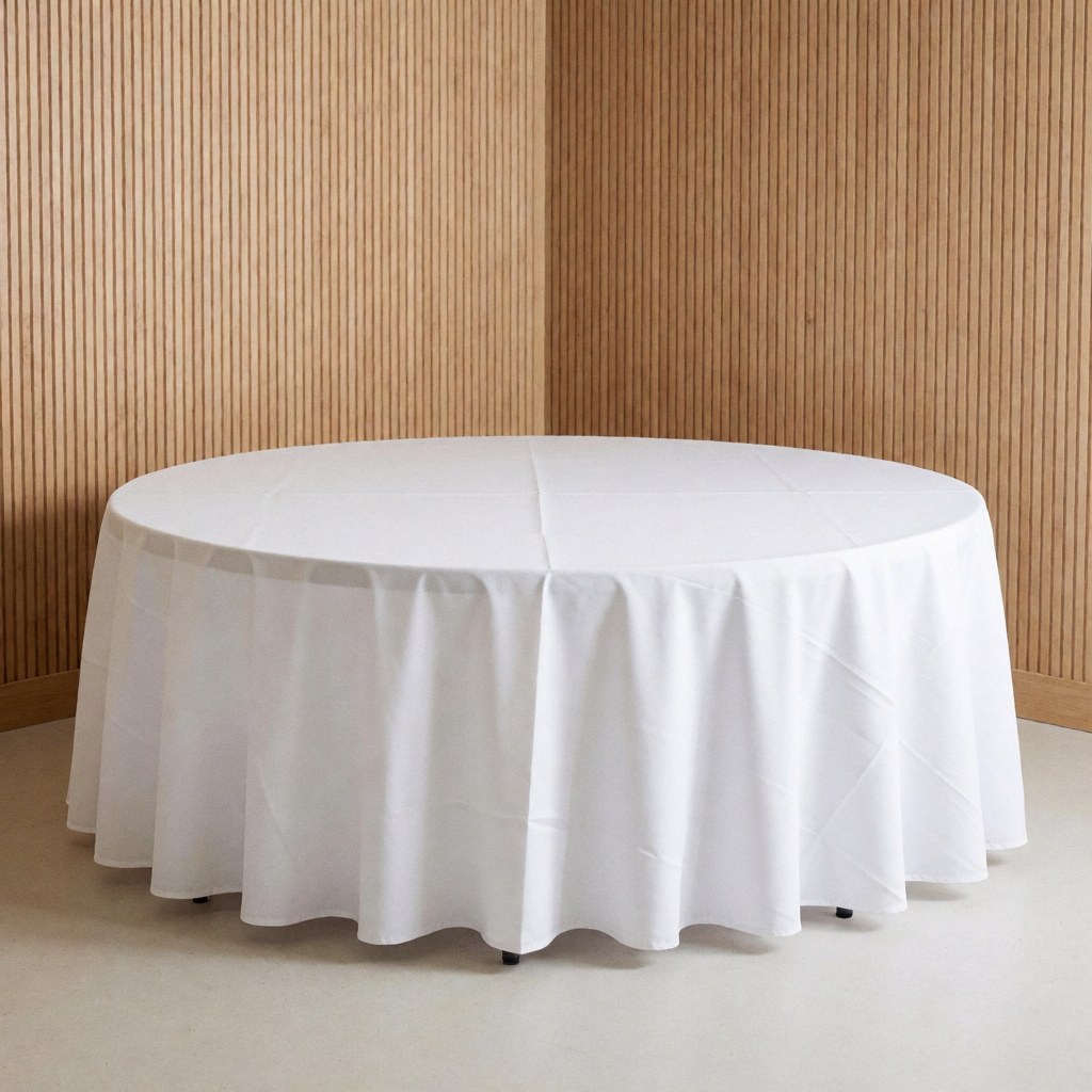 Round table covered with a white tablecloth on a light floor with wooden slat walls, suitable for event furniture rental