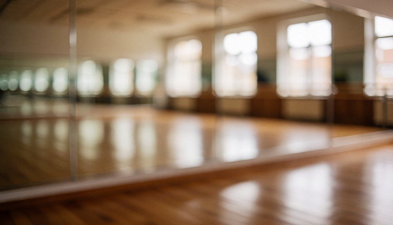 Empty gymnastics studio background featuring large mirrors, wooden flooring, and windows, suitable for text overlays about gymnastics classes.