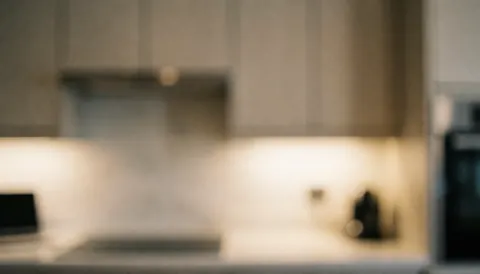 Blurred modern kitchen background featuring warm lighting, cabinets, and appliances, suitable for text overlays.