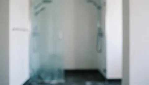 Blurred background of a bathroom under construction featuring white walls, dark flooring, and diffused lighting, suitable for commercial text overlays.