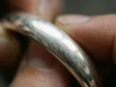 Macro detail of a silver bracelet with visible texture and scratches held by hands for homeopathy products