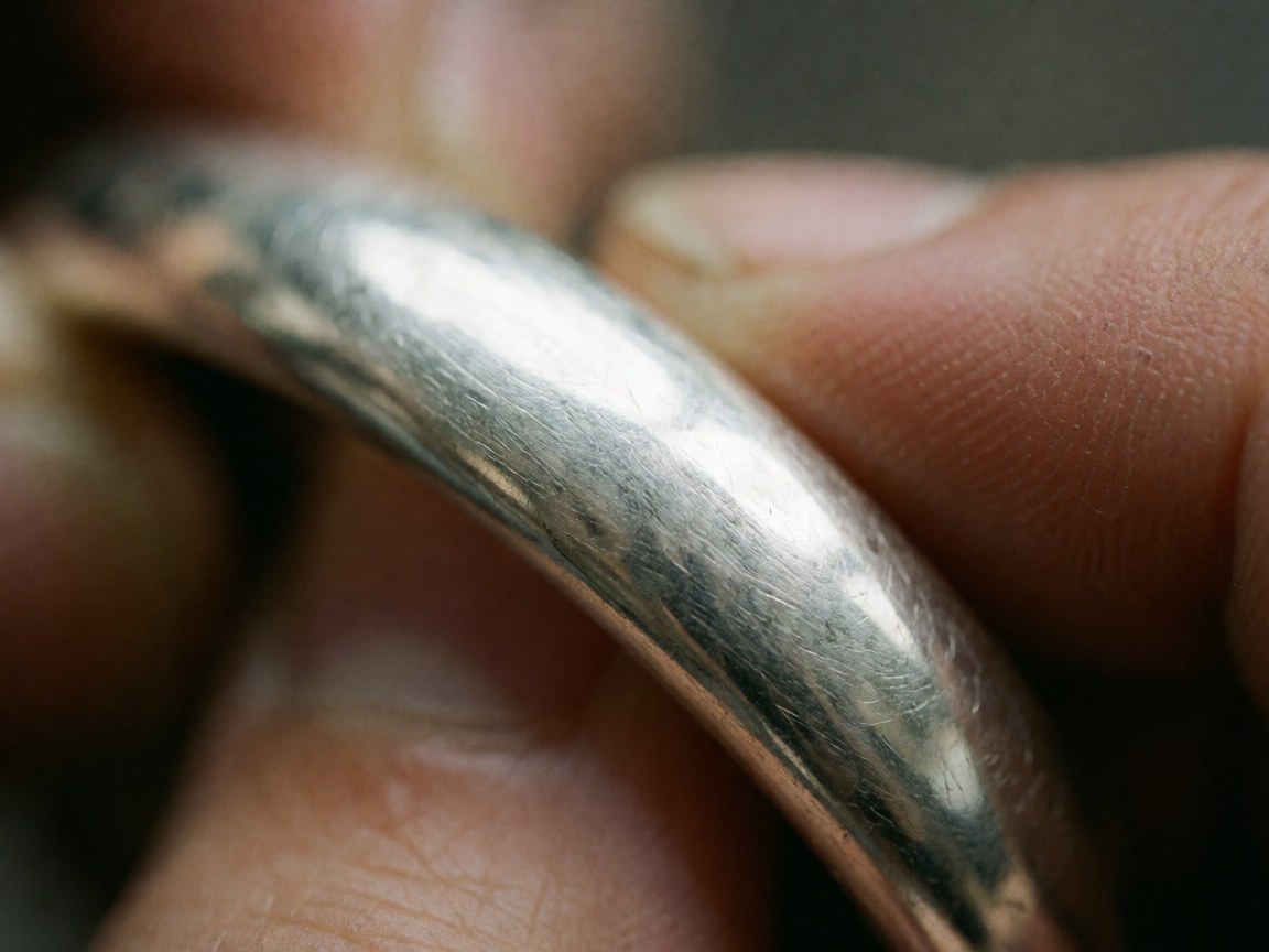Macro detail of a silver bracelet with visible texture and scratches held by hands for homeopathy products
