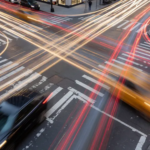 Long exposure image of a city street intersection showing light trails from vehicles, ideal for dynamic photography businesses.